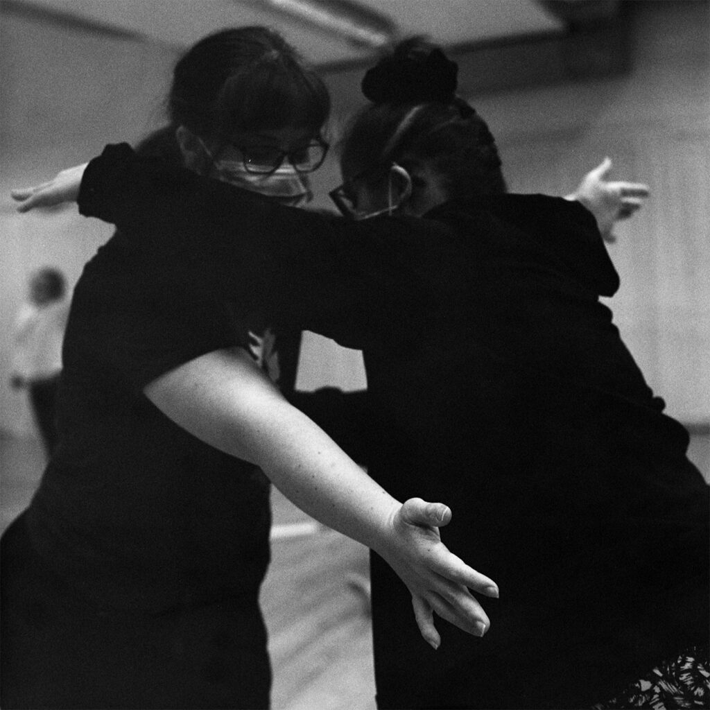 A close up image of two dancers rehearsing a duet, the image is black and white