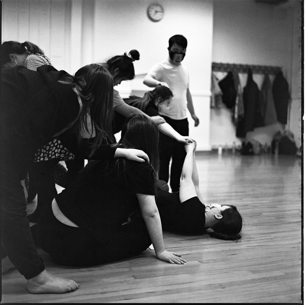 A black and white group shot of dancers in their rehearsal studio