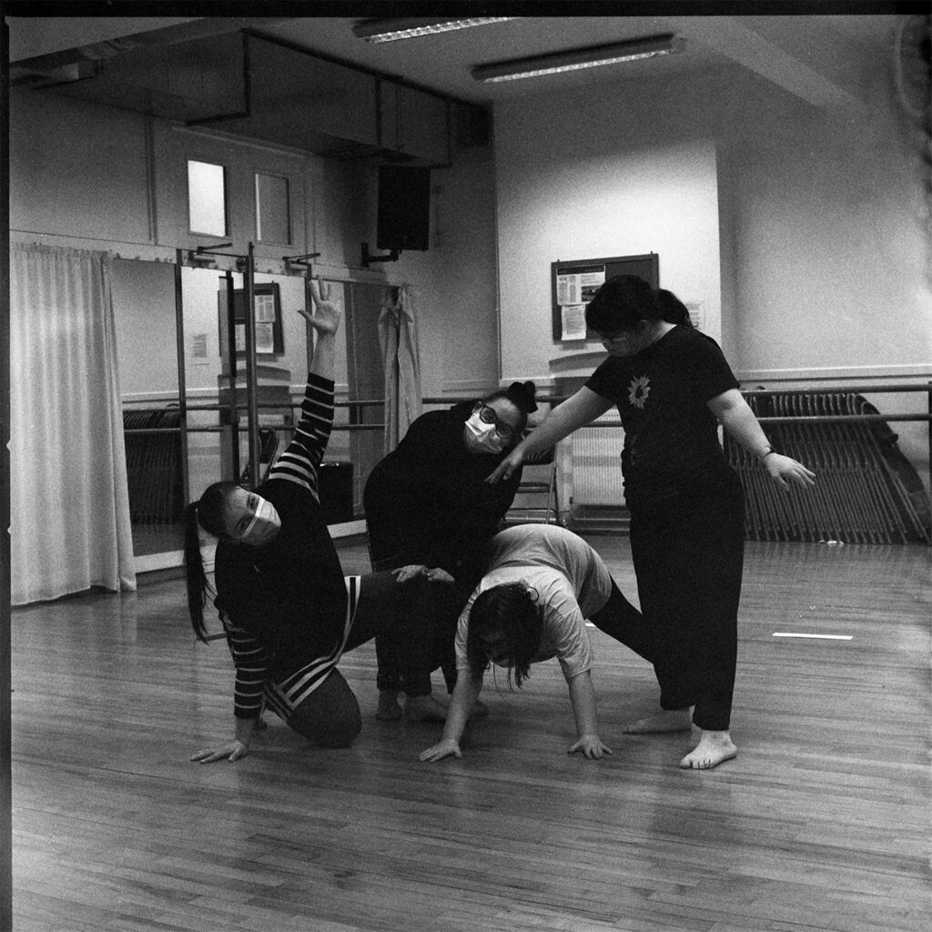 A group shot of four dancers, making a variety of shapes in the studio